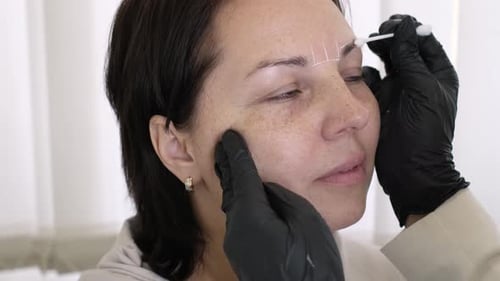 Woman Getting Eyebrows Shaped in Beauty Salon