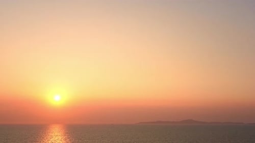 Eine große goldene Sonne geht über dem Meereshorizont unter.