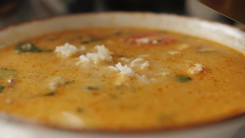 Un client d'un restaurant thaïlandais ajoute du riz dans un bol avec de la soupe Tom Yam Gros plan d'une soupe thaïlandaise