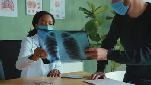 Woman Doctor Examines X-Ray with Male Patient
