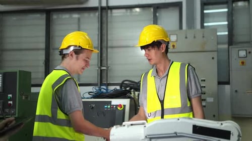 Engineer and worker shaking hands while working on industrial machine in factory