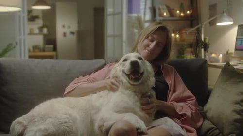 Woman Petting Large White Dog on Couch Indoors