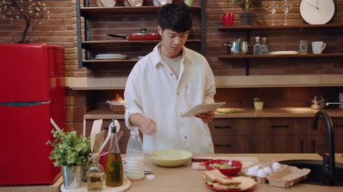 Man using tablet while cooking in kitchen