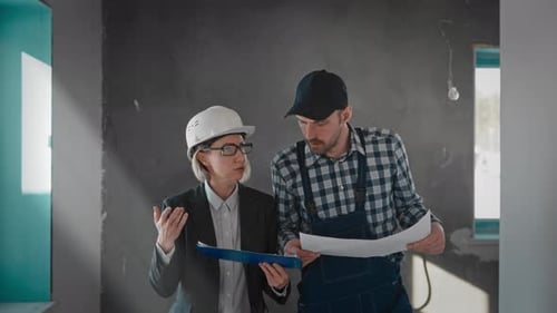 A Man in a Suit and Tie and a Woman Sharing a Blueprint at a Building Event
