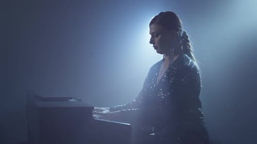 Woman Plays Piano Under Stage Lighting