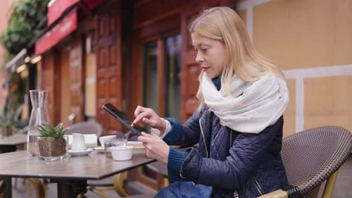 Woman Using Tablet at City Cafe Table