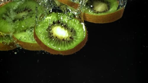 Fresh Kiwi Fruit Slices Falling Into Clear Water