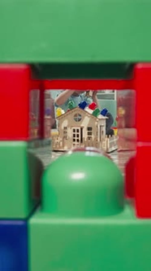 Un niño pequeño construye una casa mientras un niño en edad preescolar cuida al bebé