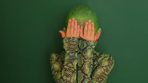 Ein Mädchen, das ihr Gesicht in Gestalt einer grünen Schlange versteckt. Das Symbol des neuen Jahres 2025