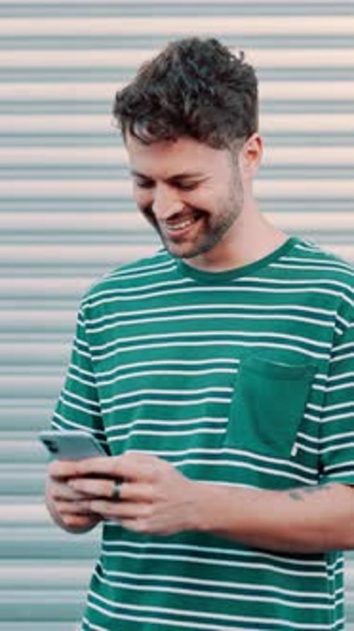Smiling Young Man Texting on a Mobile Device