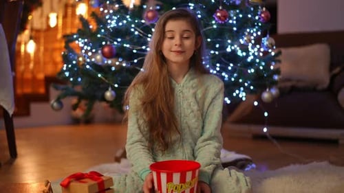Smiling Girl with Popcorn Near Christmas Tree