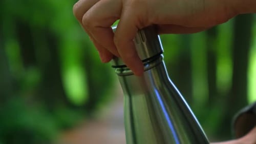 Closeup of Unrecognizable Female Hand Holding Water Bottle Reusable Steel Thermo Water Bottle in