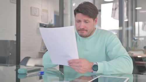 Man Reviews Documents at Office Desk