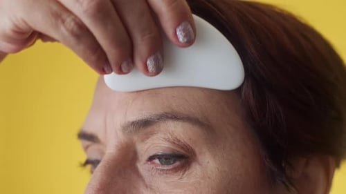 Woman Massaging Forehead with Gua Sha to Get Rid of Wrinkles