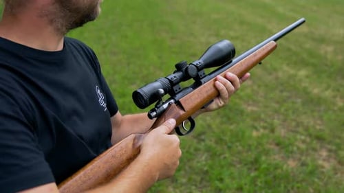 Middle aged white Caucasian man cocks cabin of hunting snipers rifle made of wood and metal and take
