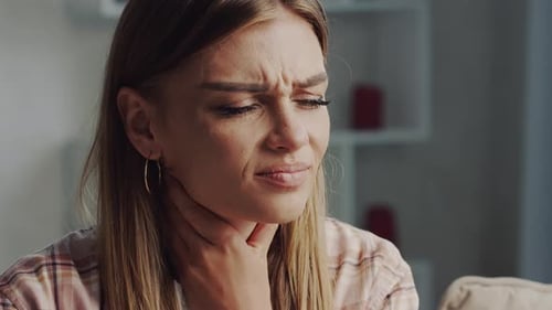 Young woman touching neck suffering from sore throat