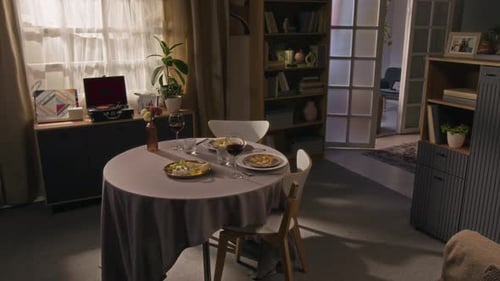 Interior of Cozy Living Room Featuring Round Table Set for Romantic Dinner