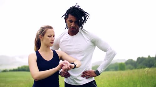 Fitness Couple Checking Smartwatch in Meadow