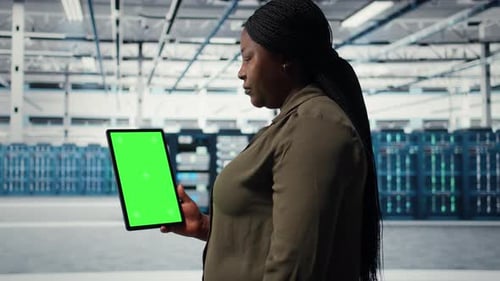 Woman Holds Tablet with Green Screen in Data Center