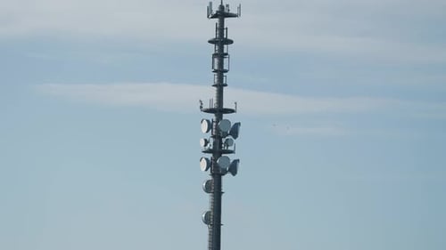 5G antenna tower against the blue sky. Slow-motion, pan follow