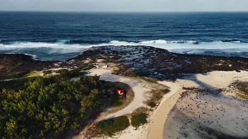 An aerial view captures a colorful kite soaring above Mauritius’ rugged coastline