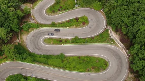 a black car running up a winding path like a bowel.