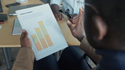 Two Black Male Colleagues Discussing Financial Summary in Office