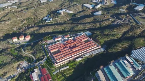 Aerial Video of a Prison at the Foot of a Mountain Surrounded By Green Plantations and a Scenic