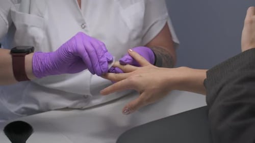 Manicurist Cleaning Client's Nails in Salon