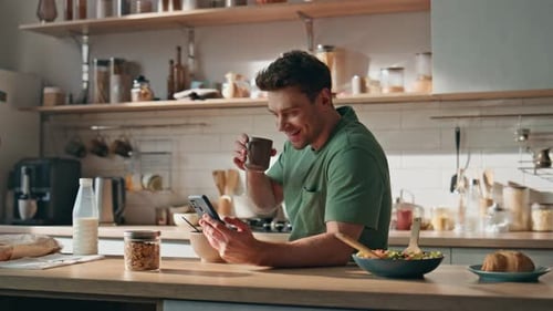 Young Man Using Phone in Kitchen During Breakfast