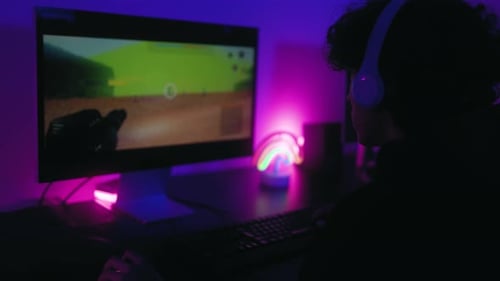 Person Plays First-Person Shooter in Purple Lit Room