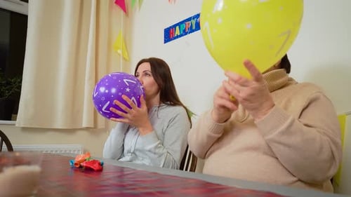 Two Women Inflate Balloons for Birthday Celebration