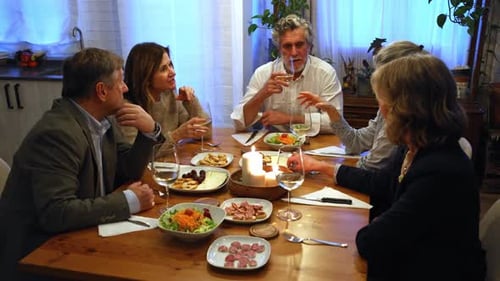Friends gather around dinner table with candlelight