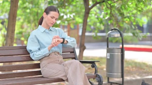 Woman on Park Bench Checking Smartwatch