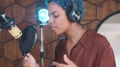 Young African American Woman Rapping Stands in Recording Studio with Microphone