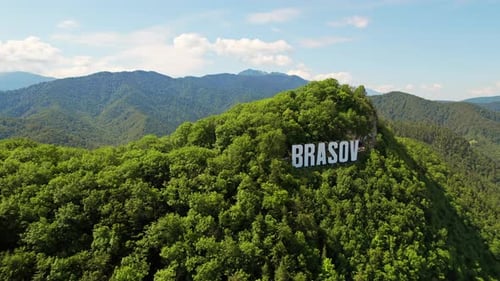 Brasov sign on the top of the hill near the city, green trees, tourists, Romania