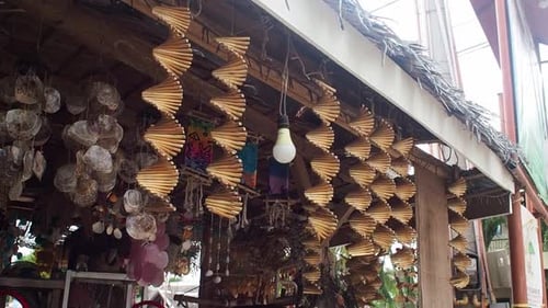 Decorative wooden helix kinetic wind spinners hanging at the front of a tropical souvenir shop. Medi