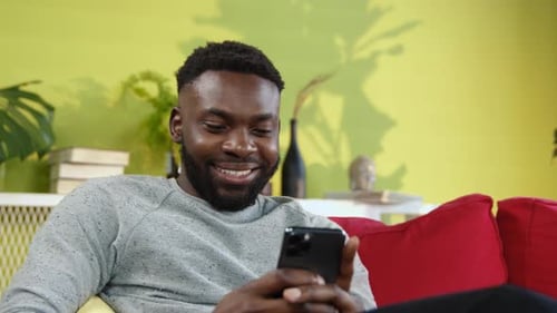 Man Relaxing on Couch Using Mobile Phone