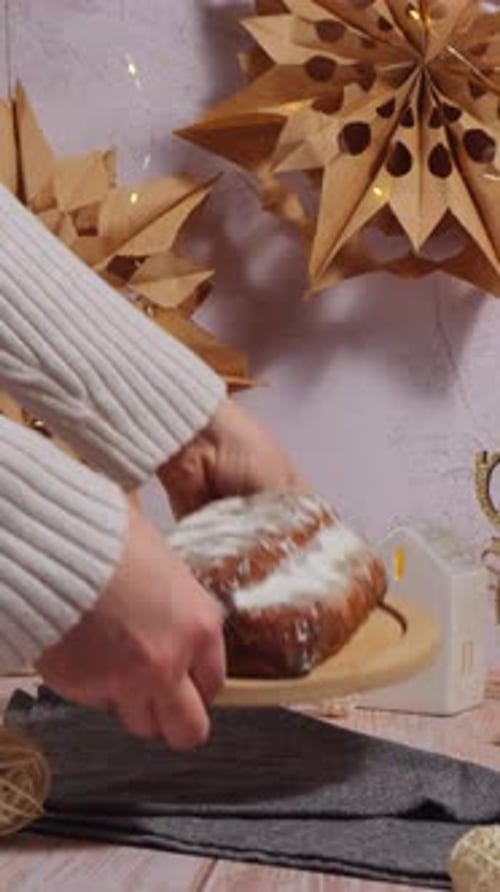 Female Hand Put Christmas Stollen in Christmas Lights and Decoration on Table Vertical Traditional
