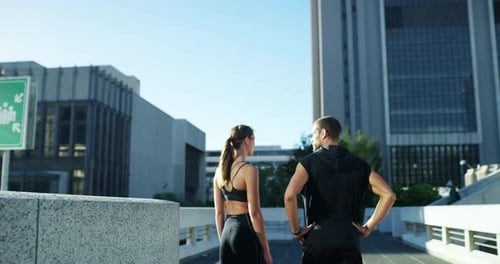 4k video footage of an athletic young couple out jogging in the city