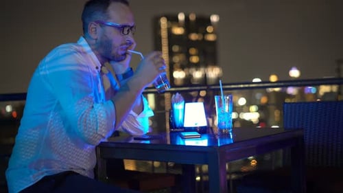 Impatient Man Waiting for Someone in Bar at Night, Checking Phone And