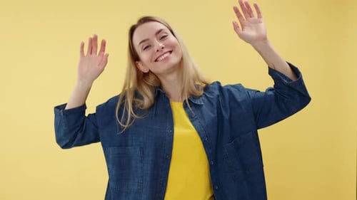 Cheerful Woman Dancing and Having Fun with Raising Hands Up in Studio Setting