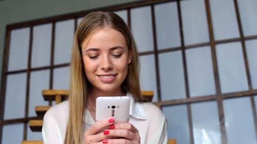 Smiling Woman Using Smartphone Indoors