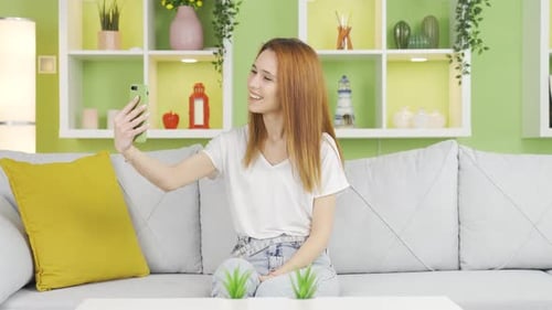 Young Woman Posing for Smartphone Selfies on Sofa