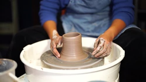 Closeup View of Potter's Hands with Working with Wet Clay on a Pottery Wheel Making a Clay
