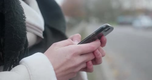 Close up profile shot of a girl texting on her black phone. Sideways, he fingers are typing. Steady