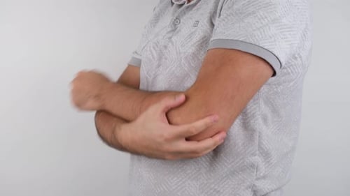 Man Rubs Aching Elbow