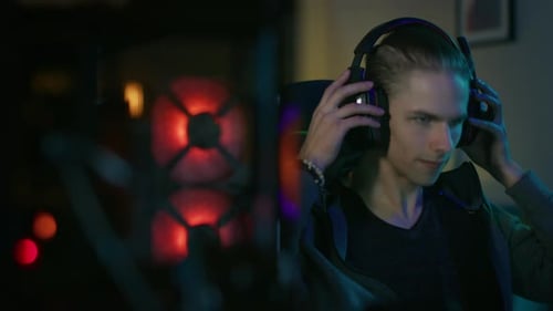 Young Man Gaming Wearing Headphones at Night