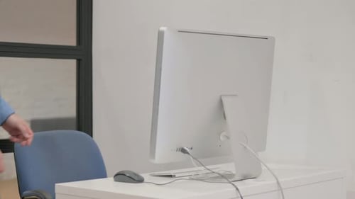 Young Man Coming to Office and Starting Work on Desktop