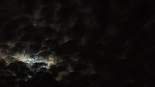 Eerie Moon Shines Through Dark, Cloudy Night Sky